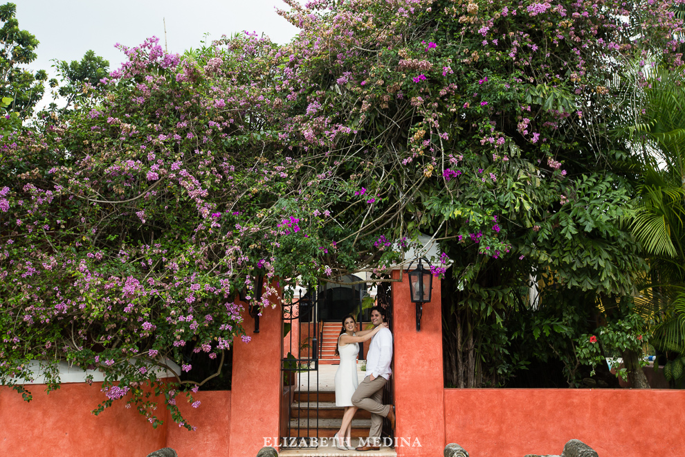 engaged couple surrounded by bouganvillia and a bright orange wall in Mexico